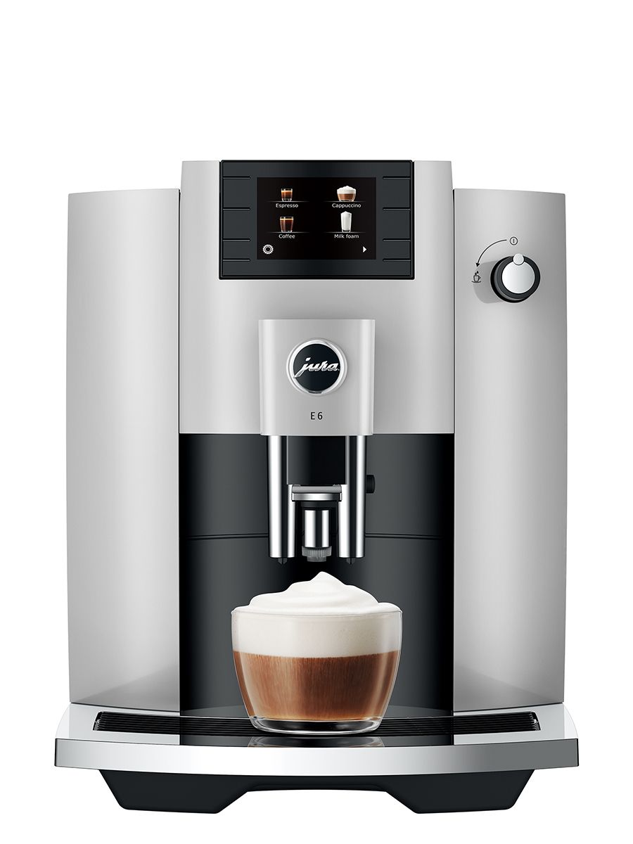 Jura E6 Platinum NAC espresso machine, front view showing the drip tray, control panel, and freshly dispensed cappuccino in a clear glass