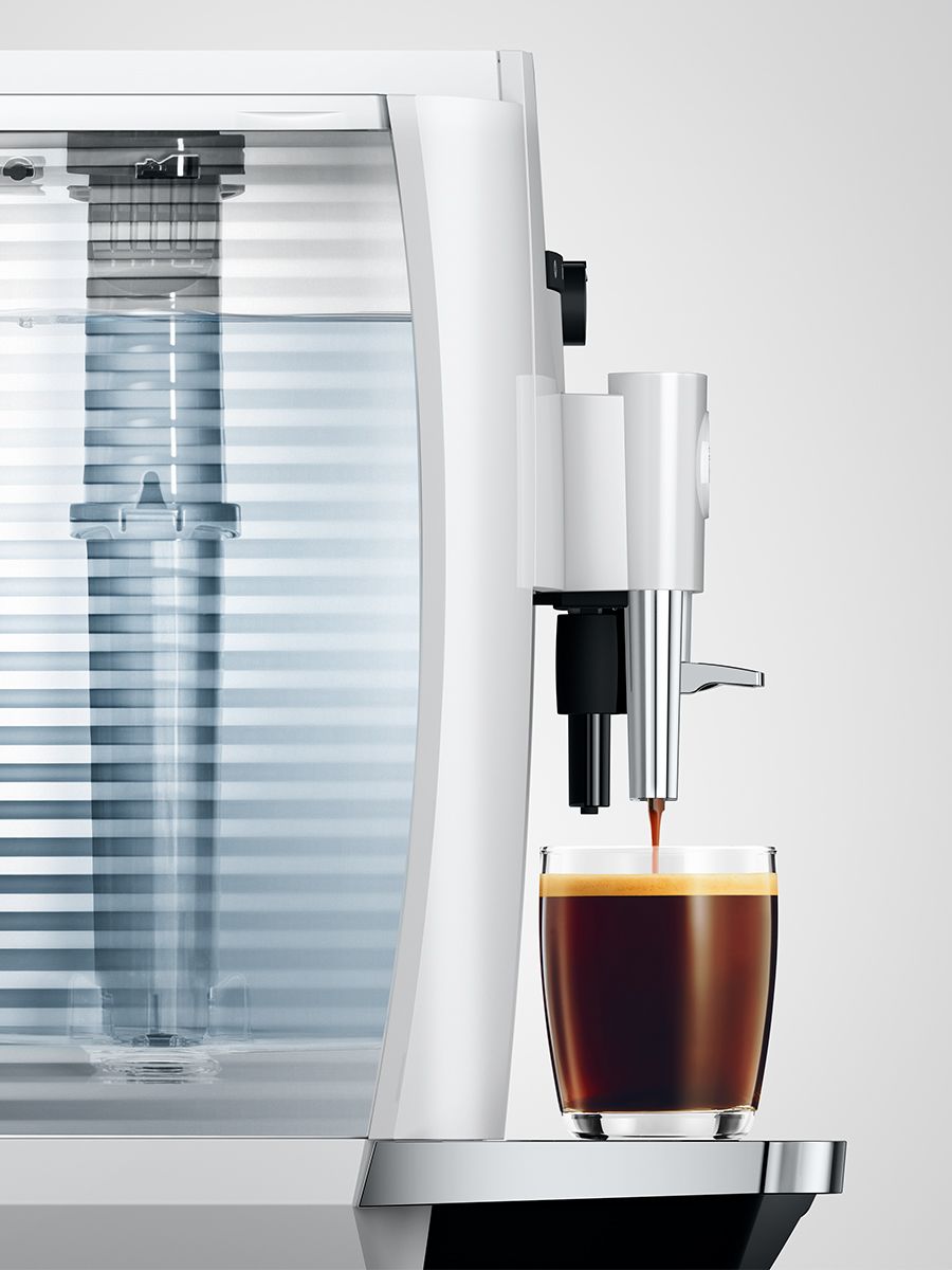 Close-up of Jura E4 Piano White showing the water tank and espresso pouring into a cup